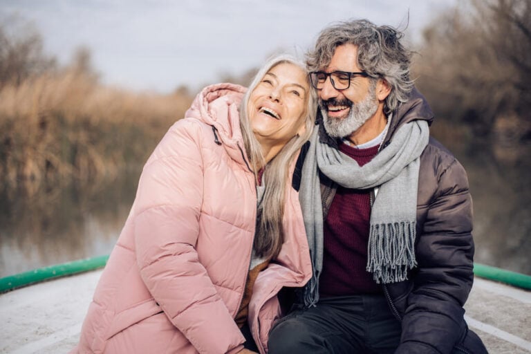 Boat deck, laughing older couple close together, mid-frame, daylight, editorial travel photo, two people.