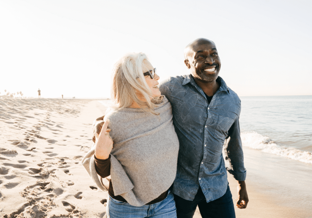man and woman strolling on the beach enjoying emotional Stages of Retirement