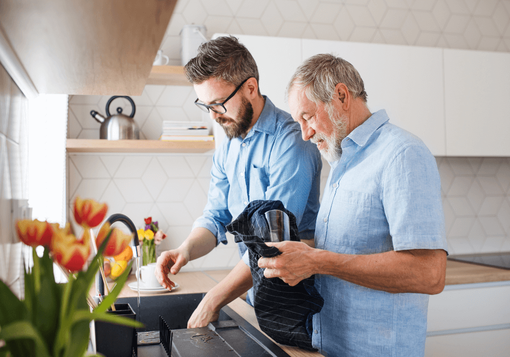 senior father with mature son washing dishes walking away from elderly parent