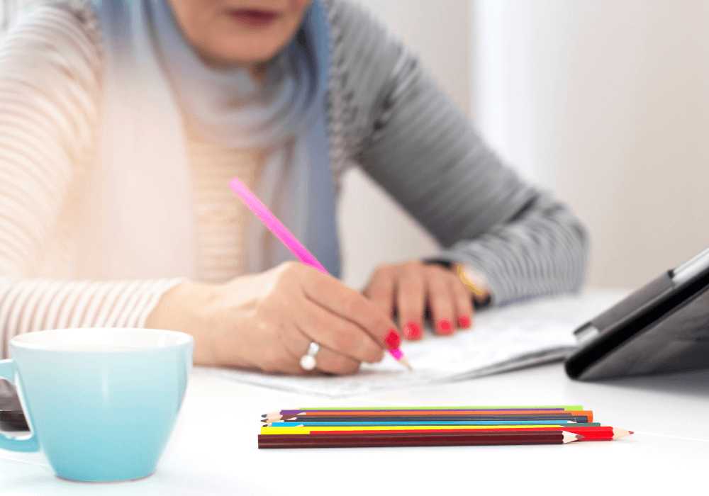 Desk interior, hand writing with pink pencil, close-up on stationery, daytime natural light, documentary style, single person.