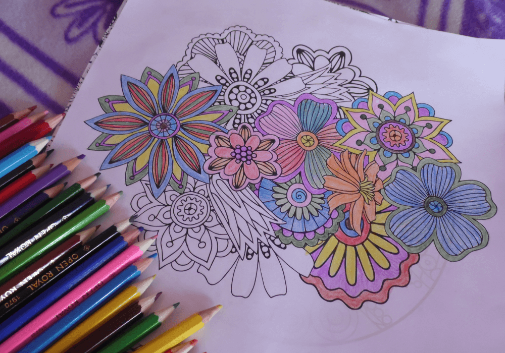 Art studio table, floral coloring page centerpiece, colored pencils left, bright afternoon light, documentary style, no people.