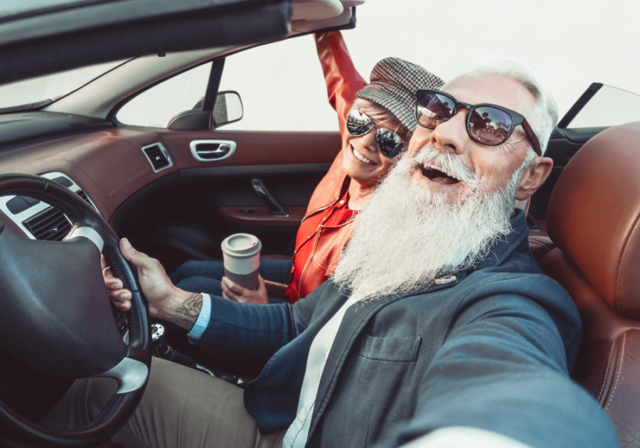 Convertible car, older couple selfie, front seat framing, sunny afternoon, editorial travel photo style, people present.