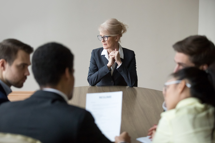 Conference room, woman in business suit foreground, round table composition, daylight, documentary style, group of people.