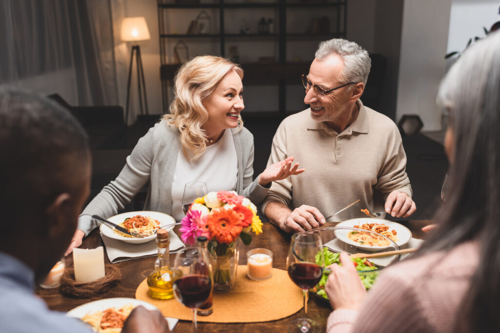 Dining room, pasta meal centerpiece, intimate table setting with candles and wine, warm evening light, editorial travel photo, four adults.