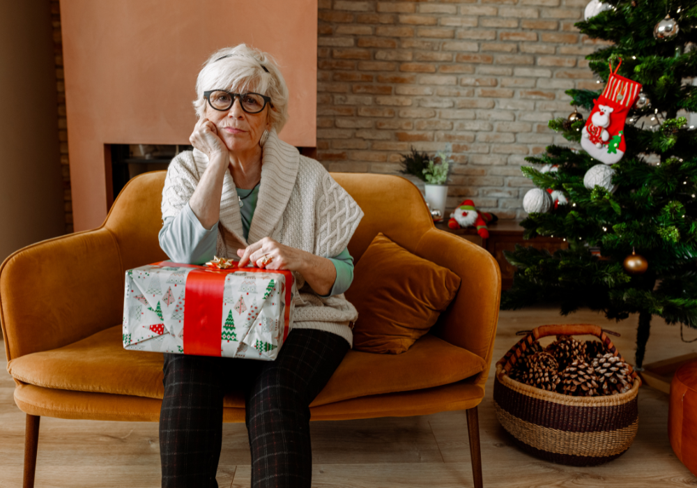 Holiday living room, sofa scene, Christmas tree and ornaments foreground, soft indoor light, documentary style, solitary elderly woman.