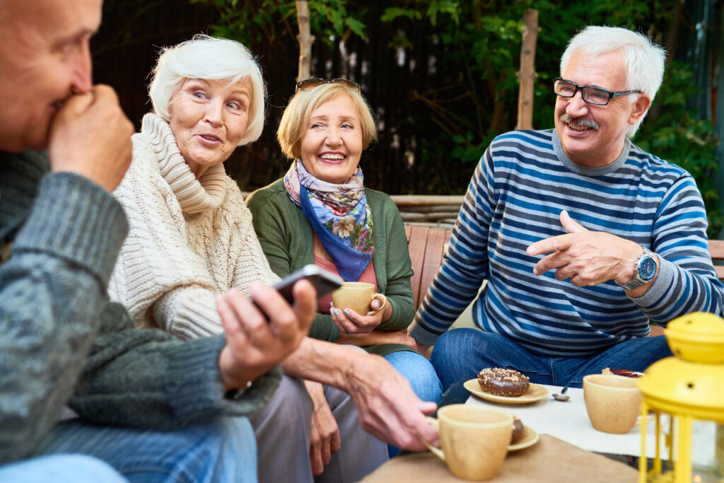 Outdoor patio, group of seniors sharing coffee and pastries, relaxed mood, natural daylight, editorial travel photo, people.
