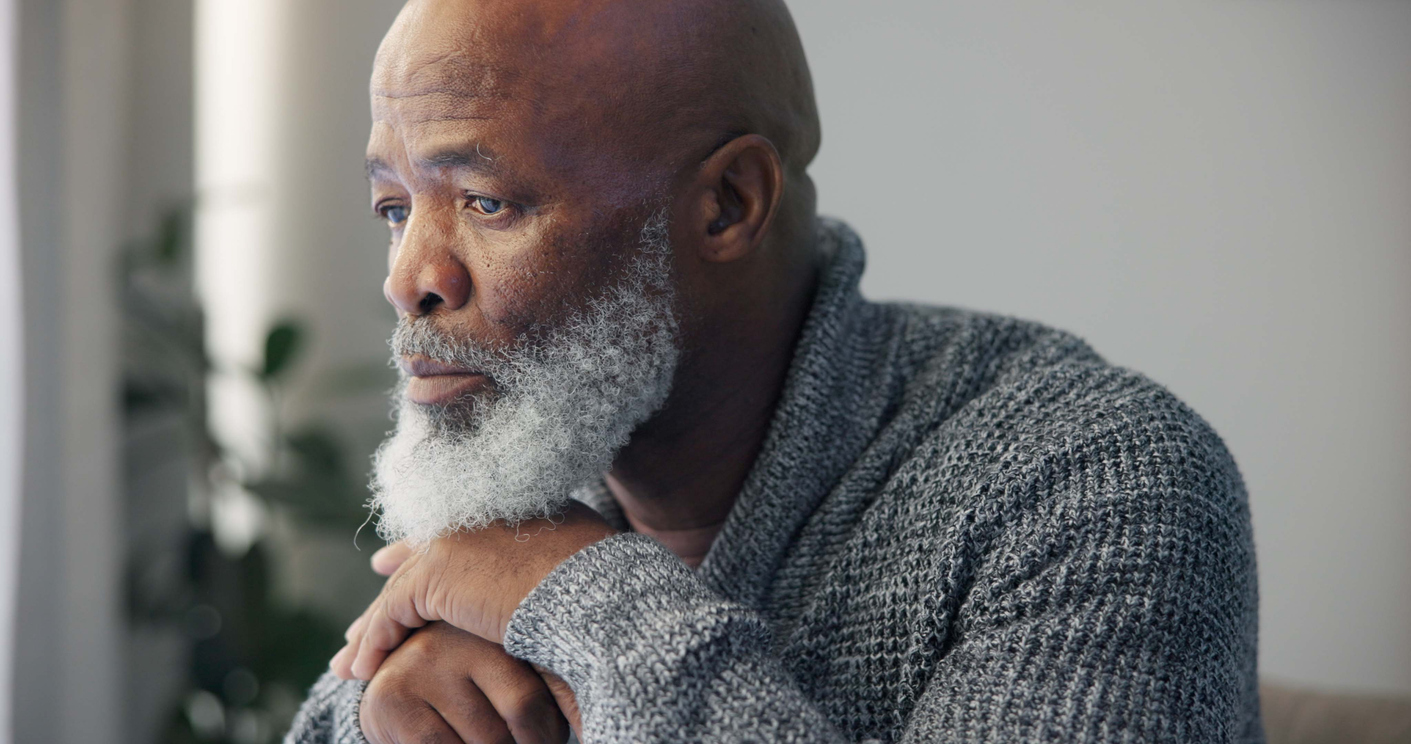 Softly lit room, older man with gray beard, close-up portrait, gentle ambient light, editorial style, one person.