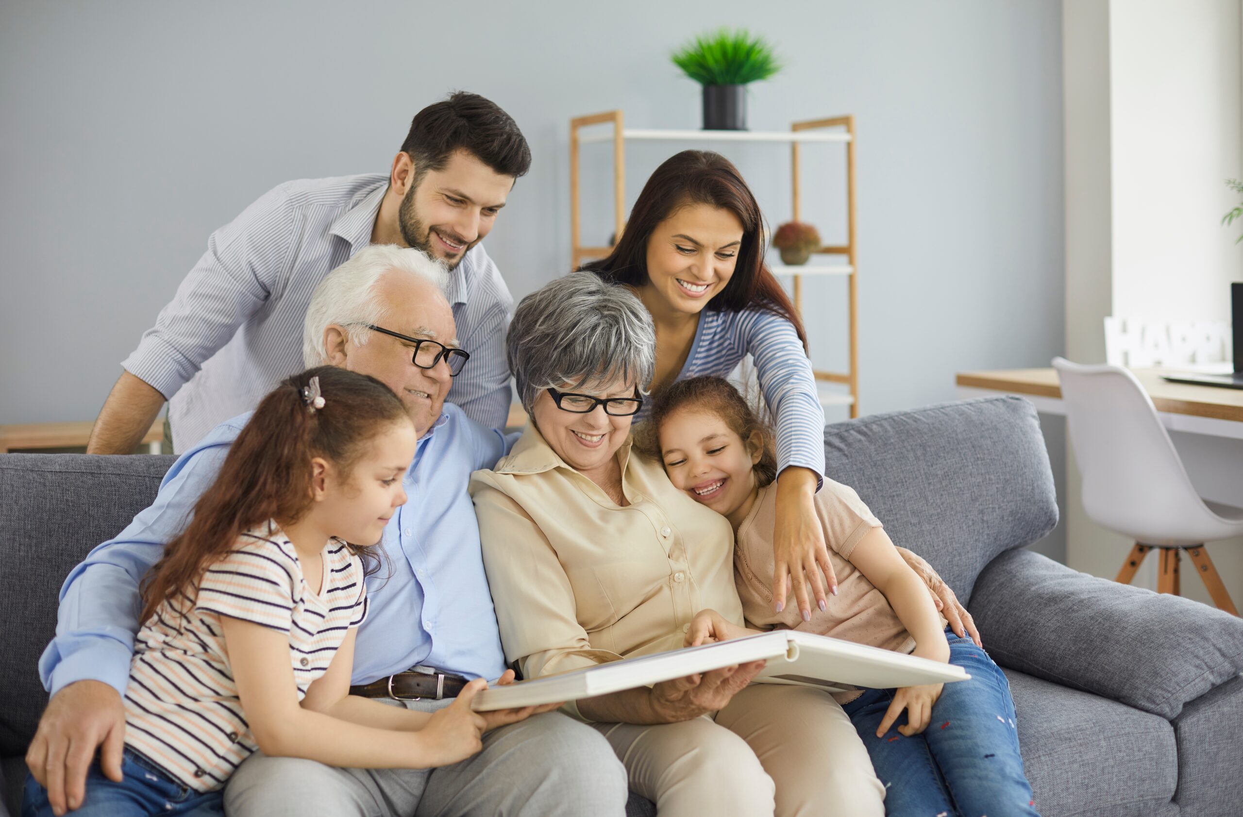 Cozy living room, family photo album, three generations on couch, daylight warmth, documentary style, people present.