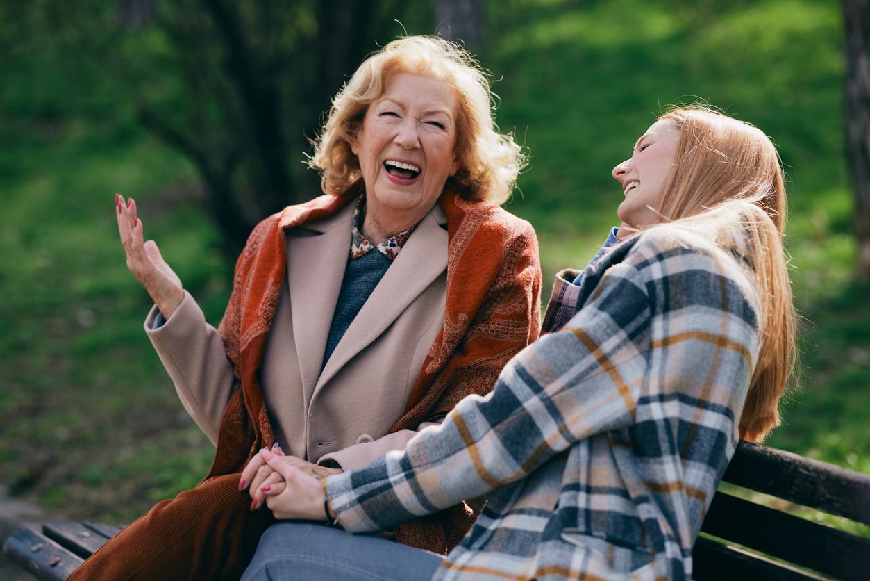 Park bench, women holding hands, close composition, daylight, editorial travel photo, people.