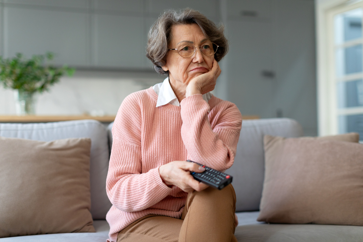 Living room, older woman with gray hair and glasses, pink sweater, morning light, documentary style, single person.