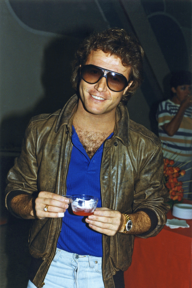 Cafe scene, man with curly hair and sunglasses at red table, midday light, editorial travel photo, two people.